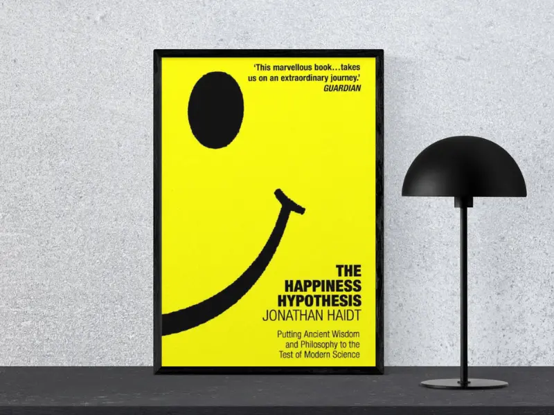 The Happiness Hypothesis by Jonathan Haidt Book cover of The Happiness Hypothesis by Jonathan Haidt, featuring the subtitle ‘Tiny Changes Remarkable Results’, displayed in a black frame next to a modern black lamp, highlighting.