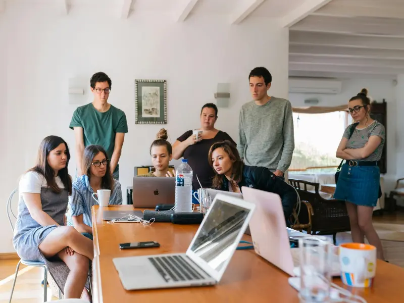 The Hidden Superpower of Youth A group of young professionals gathered around a laptop in a bright room, collaborating and observing closely—capturing the power of observation in teamwork, learning, and innovation.